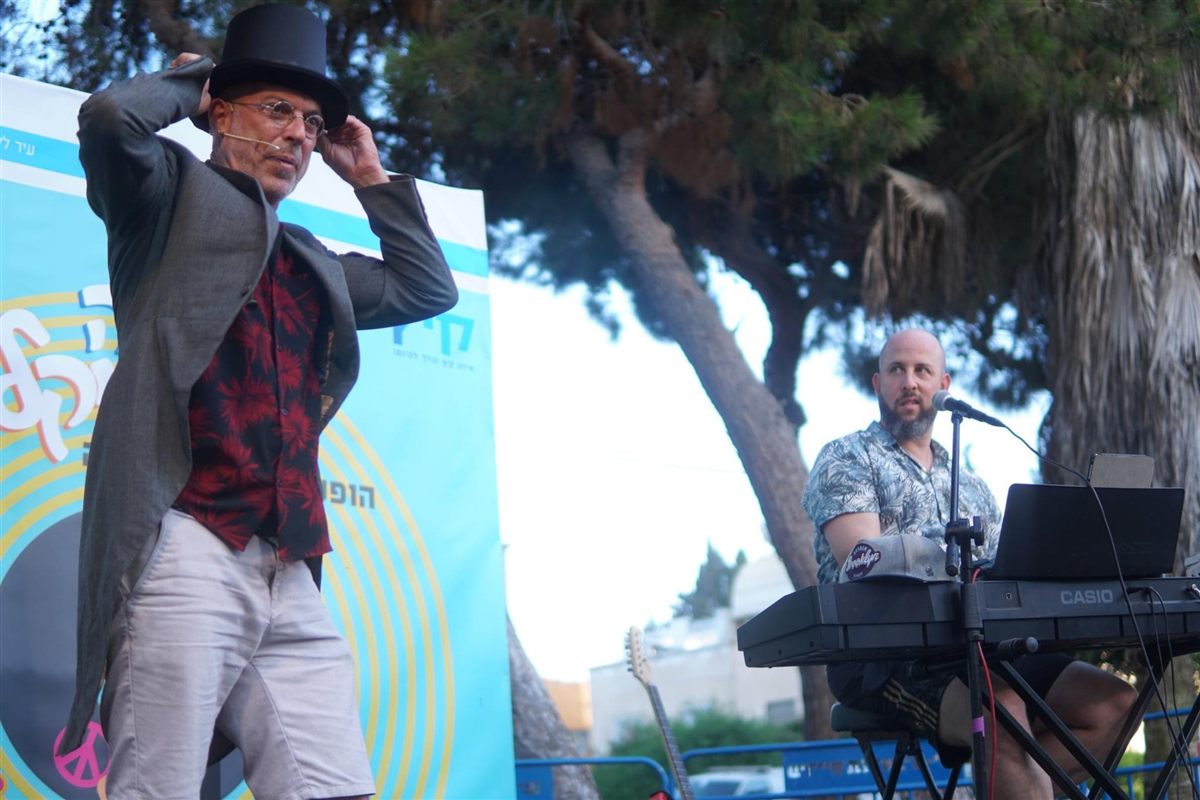 רגע תיאטרלי במסיבת גיטרות – שחקן עם מגבעת ונגן קלידים