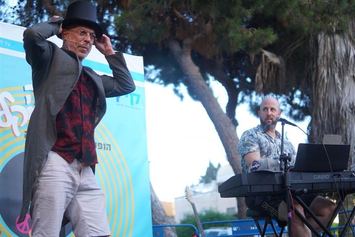 רגע תיאטרלי במסיבת גיטרות – שחקן עם מגבעת ונגן קלידים